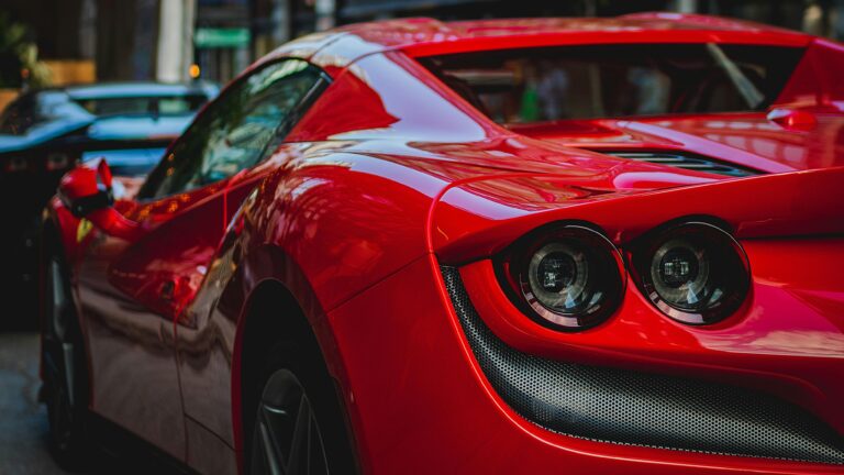 Close-up shot of a luxurious red sports car showcasing its sleek design and shiny surface.